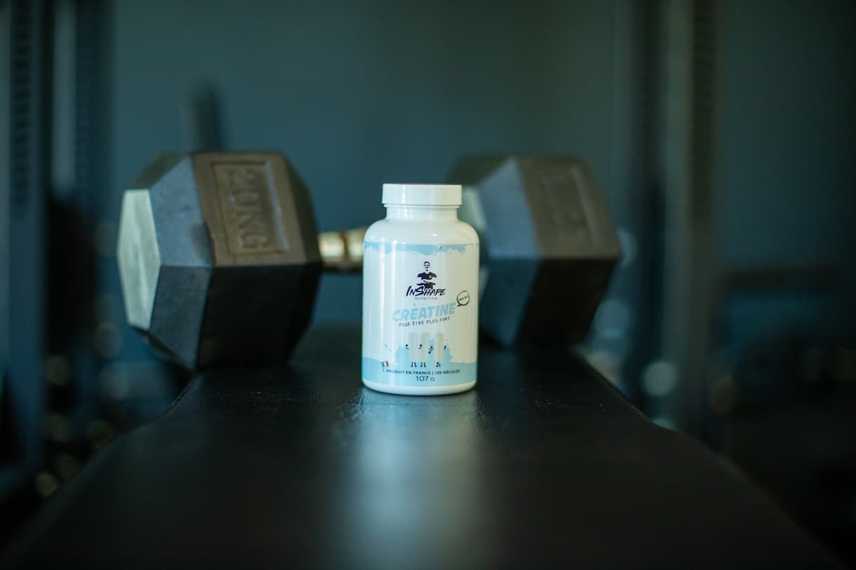 Créatine Inshape Nutrition posée devant un halter